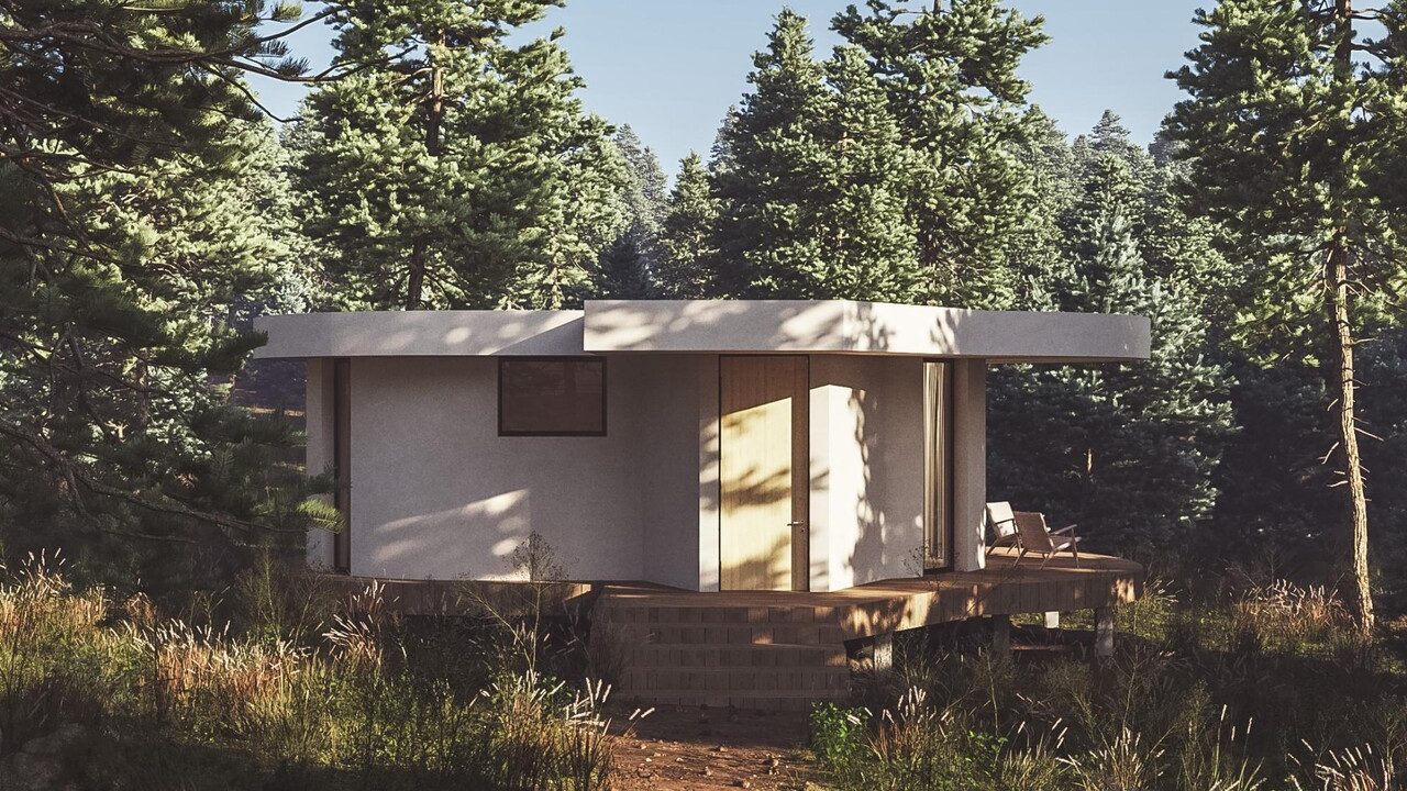 A small white modern cabin surrounded by trees